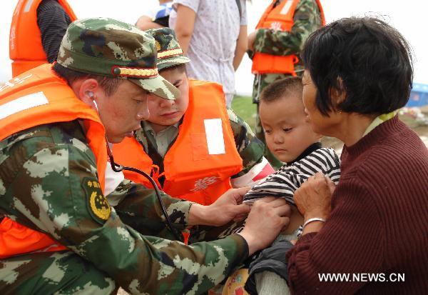 Armed policemen treat a boy injured in the flood in Fuzhou City, east China's Jiangxi Province, June 22, 2010. The heavy rains and floods ravaging 10 southern Chinese provinces had killed 199 and left 123 missing as of Tuesday, according to the Ministry of Civil Affairs. [Xinhua]