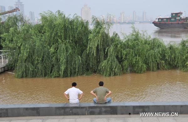  Two residents sit by the Ganjiang River as parts of the trees along the river is dunked by the flood, in Nanchang City, east China's Jiangxi Province, June 22, 2010. The flood peak of Ganjiang River is expected to pass Nanchang in the early morning on June 23.