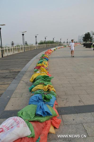 A resident walks along the sandbags in Qiushui Square located by the Ganjiang River, in Nanchang City, east China's Jiangxi Province, June 22, 2010. The flood peak of Ganjiang River is expected to pass Nanchang in the early morning on June 23.
