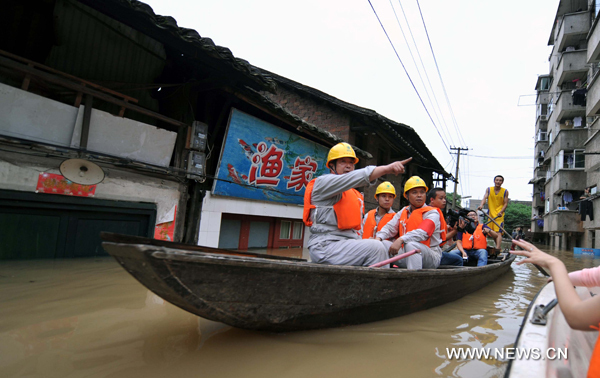 Employees of local power administration check the power lines in the flood in Xiangtan County, central China&apos;s Hunan Province, June 24, 2010. Torrential rain and more water from its upper reaches had greatly driven up water levels in the Xiangjiang River. [Xinhua]