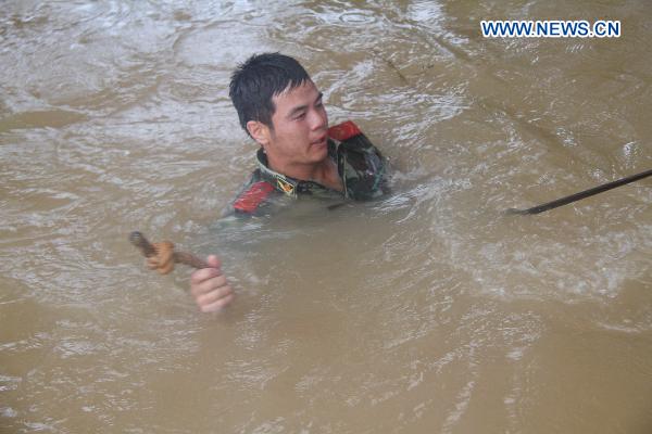 An armed policeman battles the torrents as a contingent of armed policemen with the Ji&apos;an City&apos;s Detachment convey and pile up sand bags in a rush consolidation of the Fangzhou Batardeau to contain the tempestuous and surging Ganjiang River, at Liujiacun section, in Ji&apos;an City, east China&apos;s Jiangxi Province, June 24, 2010. [Xinhua]