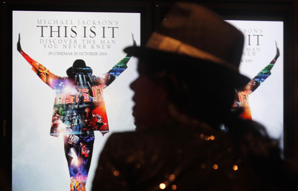 A Michael Jackson fan waits next to electronic posters at the Australian premiere of the documentary 'This Is It', in Sydney October 28, 2009. The documentary includes interviews, rehearsals and backstage footage of Michael Jackson as he prepared for his shows in London. The film opens in Australia on October 29.
