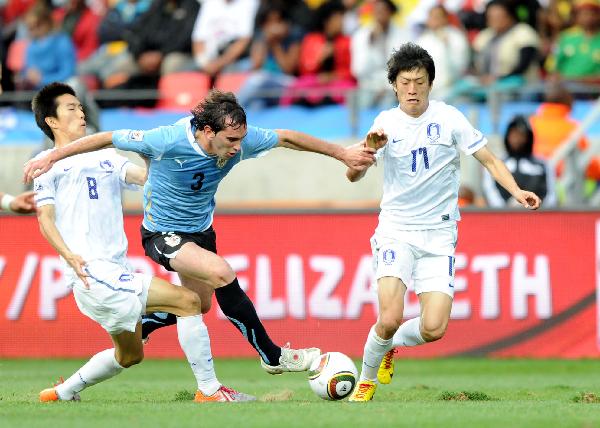 Uruguay's Diego Godin (C) vies with Kim Jung-Woo (L) and Lee Chung-Yong of South Korea during the 2010 World Cup round of 16 soccer match at Nelson Mandela Bay stadium in Port Elizabeth, South Africa, on June 26, 2010. (Xinhua/Chen Haitong)