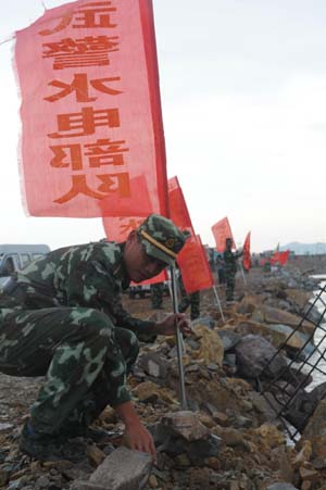 Chinese armed policemen put red flags on the Changkai Dike which is just repaired in east China&apos;s Jiangxi Province June 27, 2010. [Xinhua] 