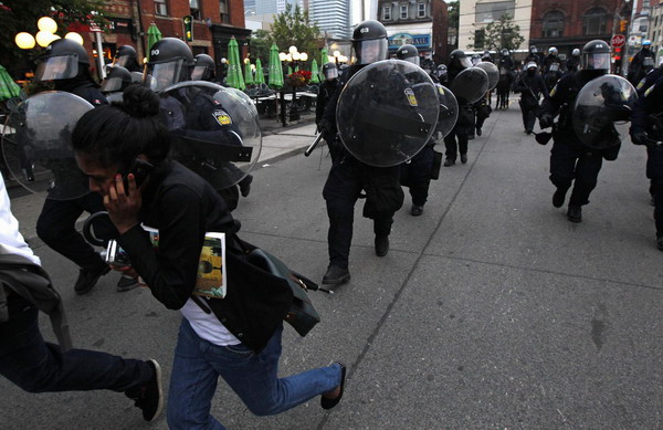 Protestors run from the police during a demonstration against the G20 summit in downtown Toronto June 26, 2010. [China Daily/Agencies]