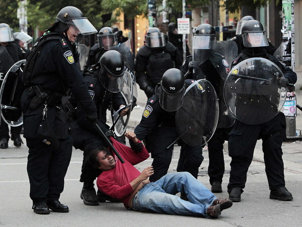A protestor is taken down by police in riot gear during a protest against the G20 summit in downtown Toronto, June 26, 2010. [China Daily/Agencies]