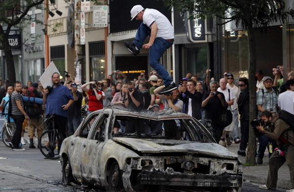 A protestor leaps on a burned out police vehicle during a demonstration against the G20 summit in downtown Toronto Canada June 26, 2010. [China Daily/Agencies]