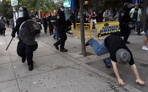  Police rush at protesters demonstrating against the G20 summit as a police vehicle burns in downtown Toronto June 26, 2010. [China Daily/Agencies] 