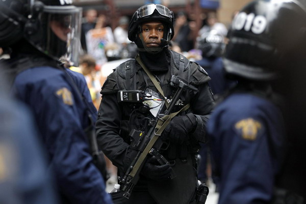 A police officer stands with a weapon during demonstrations against the G20 summit in downtown Toronto June 26, 2010. [China Daily/Agencies]