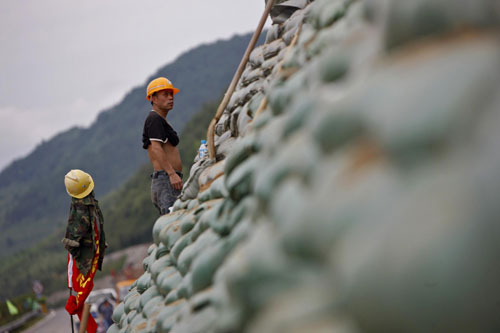 Workers construct sandbags in Jianyang, East China&apos;s Fujian province, June 27, 2010. Days of torrential downpour resulted in a 50-meter crack beneath a section of expressway in Jianyang. To prevent a landslide, workers piled up sand bags clinging to the wall of the road. [Xinhua] 