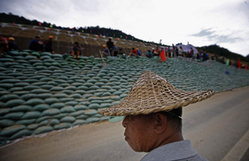  A worker watches the sandbag construction along the protecting wall in Jianyang, East China&apos;s Fujian province, June 27, 2010. [Xinhua] 