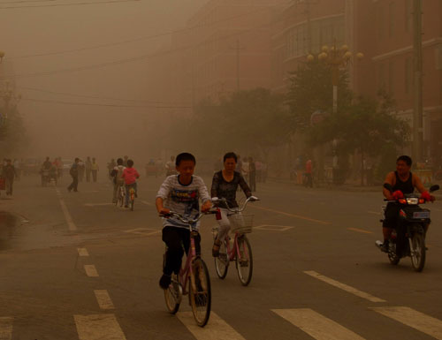 Bicyclists ride through a sandstorm in Wuwei, Northwest China&apos;s Gansu province, June 27, 2010. [Xinhua]