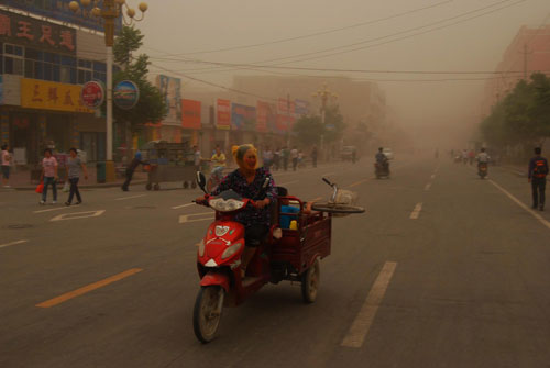 A motor biker rides through the sandstorm with a kerchief covering her head in Wuwei, Northwest China&apos;s Gansu province, June 27, 2010. [Xinhua]