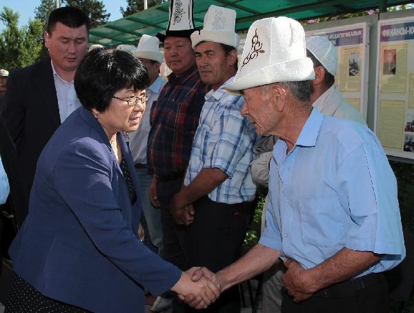 Kyrgyzstan interim leader Roza Otunbayeva (L Front) greets a group of ethnic Kyrgyz citizens at a polling station on the day of the constitutional referendum in the southern city of Osh, Kyrgyzstan, on June 27, 2010. [POOL/Xinhua]