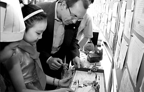 Michael Koenig (second from right), president of Bayer Group for Greater China, studies an environmentally-friendly themed work of art by pupils at a primary school in Shanghai. Focusing on the environment and educating the young about how to protect the environment has been a core aim of Bayer for more than 100 years. [China Daily] 