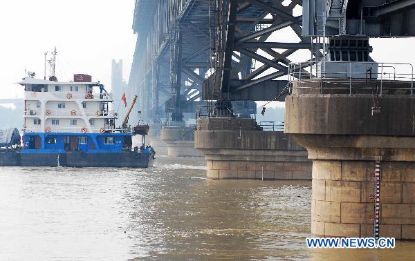 A vessel sails across a bridge on the up-surging Yangtze River at the section of Jiujiang, east China&apos;s Jiangxi Province, June 27, 2010. The water level on the trunk stream of the Yangtze River in the Jiujiang section rose to 20.18 meters by 19 o&apos;clock on the day, 0.18 meters above the alert level, with a corresponding flows rate as quick as 40,300 cubic meters per second, as an aftermath of previous persistent strong downpour, for the first time since 2003. [Xinhua] 