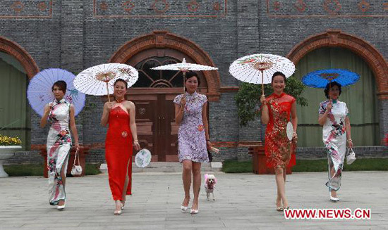 A quintuplet of female contestants perform cat walk in the show of Cheong-sam, or Chi-pao, a close-fitting woman's dress with high neck and slit skirt, in Zhenjiang City, east China's Jiangsu Province, June 27, 2010. More than 30 female contestants take part in the Floral Viva final contest of the Chi-pao show, on the scenic archaic street of Xijindu to evoke a sense of nostalgia. [Xinhua photo]