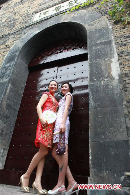 A pair of female contestants strike posture in the show of Cheong-sam, or Chi-pao, a close-fitting woman's dress with high neck and slit skirt, in Zhenjiang City, east China's Jiangsu Province, June 27, 2010. More than 30 female contestants take part in the Floral Viva final contest of the Chi-pao show, on the scenic archaic street of Xijindu to evoke a sense of nostalgia. [Xinhua photo]