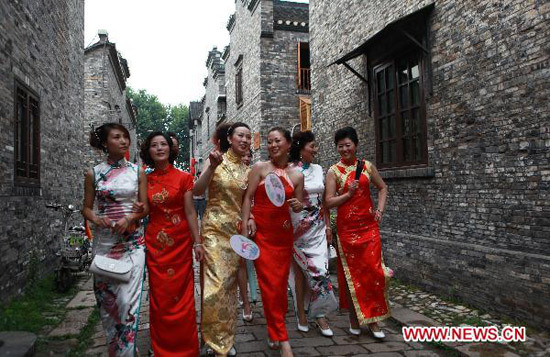 A group of female contestants perform cat walk in the show of Cheong-sam, or Chi-pao, a close-fitting woman's dress with high neck and slit skirt, in Zhenjiang City, east China's Jiangsu Province, June 27, 2010. More than 30 female contestants take part in the Floral Viva final contest of the Chi-pao show, on the scenic archaic street of Xijindu to evoke a sense of nostalgia. [Xinhua photo]