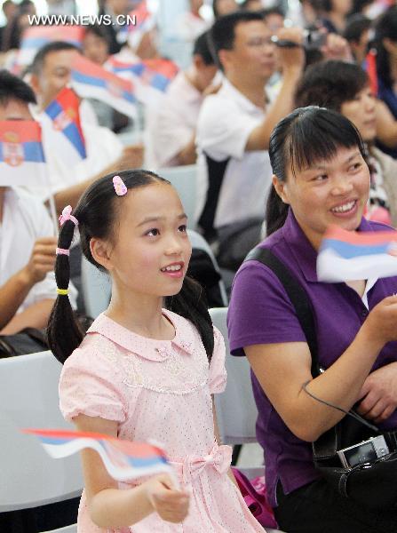 Chinese visitors wave Serbian national flags while watching performances given by Serbian artists during a ceremony marking the Serbia National Pavilion Day at the Shanghai World Expo in Shanghai, east China, June 27, 2010. 