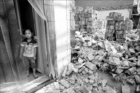A boy watches as demolition creeps near his family home. 