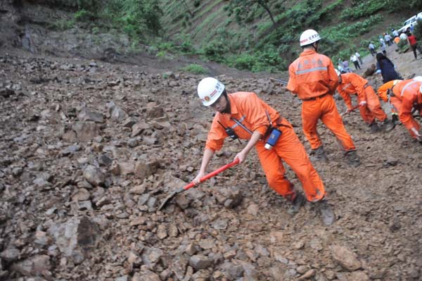 Rescuers clean up debris from the landslide which fell onto the roads leading into Dazhai Village Monday. A landslide caused by heavy rains buried at least 107 people Monday in Guanling County of Southwest China&apos;s Guizhou province and there was little hope for their survival, a local official said. [Xinhua]