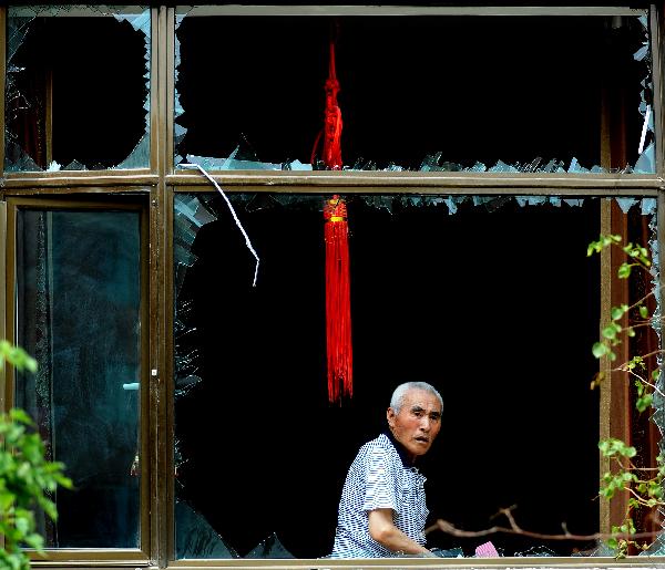 A man looks through broken windows at the blast site in Changchun, northeast China&apos;s Jilin Province, on June 28, 2010. The blast occurred in a building of Changyingshiji village in Changchun caused fire and left one dead and six injured. Now the cause of the blast is under investigation. [Xinhua]