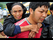 A man carries an old woman to evacuate after a rain-triggered landslide that on Monday afternoon buried about 107 people in Dazhai village of Guanling County, Southwest China's Guizhou province, on Tuesday June 29, 2010. [Xinhua]