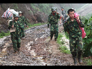 Soldiers transfer villagers' belongings after a rain-triggered landslide that on Monday afternoon buried about 107 people in Dazhai village of Guanling County, Southwest China's Guizhou province, on Tuesday June 29, 2010. [Xinhua]