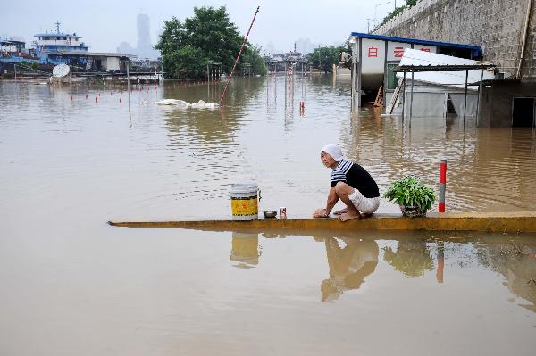 A woman washes clothes beside Ganjiang River in Nanchang, capital of east China's Jiangxi Province, on June 29, 2010. The province entered post-flood period since 10 a.m. Monday as floods have receded in many area. [Xinhua]