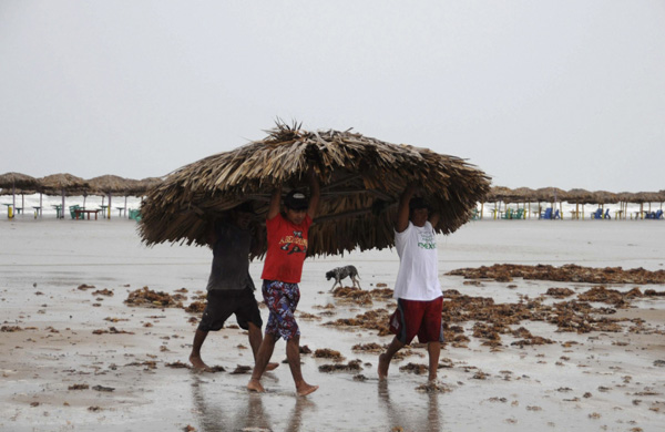 People remove the roof of a beach shelter before hurricane Alex is expected to make landfall, at Miramar beach in Tampico June 30, 2010. Hurricane Alex moved slowly in Gulf waters on Wednesday, growing stronger and likely to come ashore later in the day but sparing Mexican oil rigs and U.S. oil fields to the relief of crude markets. [Xinhua]