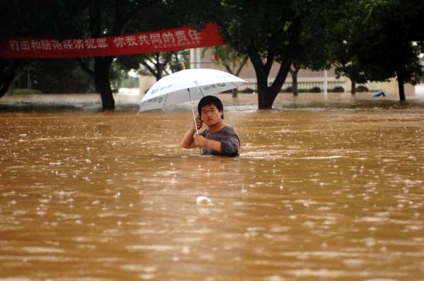 A man wade through a flooded street in Yujiang County, east China's Jiangxi Province June 20, 2010. Persistent rain in ten regions of south China has left 175 people dead and 107 missing by 8 a.m. June 21, according to the figures released by the Office of State Flood Control and Drought Relief Headquarters and the Ministry of Civil Affairs. 