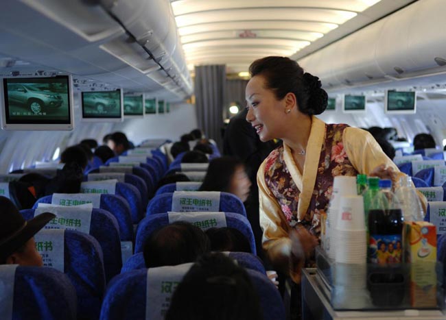 A stewardess serve passengers on the first flight to the Gunsa Airport on July 1, 2010. [Xinhua]