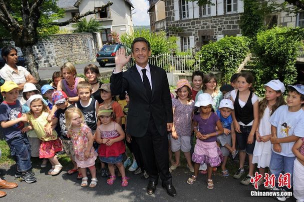 France&apos;s President Nicolas Sarkozy (C) has a photo taken with children during his visit at Mur-de-Barrez, Center France, July 1, 2010. [Chinanews.com] 