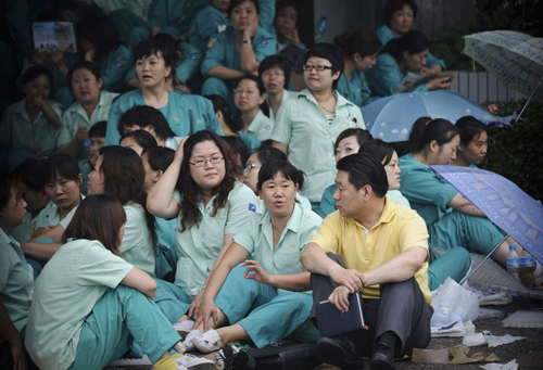 Workers in green uniforms stage a sit-in protest at the main entrance of the Mitsumi Electric Co factory in Tianjin on Thursday, July 1, 2010. [China Daily via Agencies]