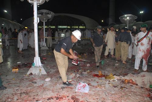 A police officer inspects the blast site in eastern Pakistani city of Lahore on July 2, 2010. At least 43 people were killed and 175 others injured in three suicide bomb attacks at a shrine in Lahore late Thursday night, according to local sources and media reports. [Jamil Ahmad/Xinhua] 