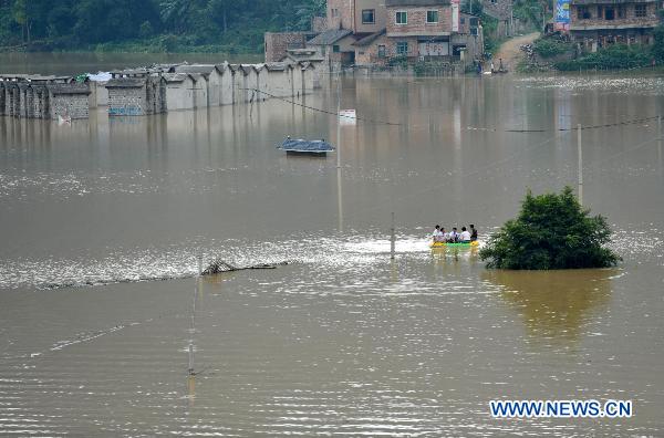 Local residents take a boat in flood water at Shali Village of Yao ethnic group in Lingyun County, southwest China's Guangxi Zhuang Autonomous Region, July 2, 2010. Torrential rainstorms ravaged Shali Village from June 27 to June 30, causing serious flood which cut off electricity, traffics and clean water supplies there. A total of 3700 mu (about 244.87 hectares) farmland had been destroyed by the flood. [Zhou Hua/Xinhua]