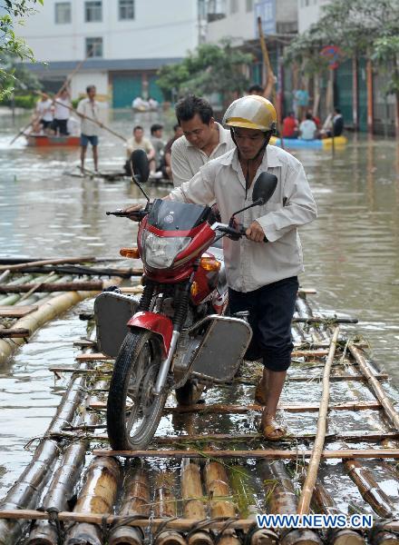 Local residents take a bamboo raft in flood water at Shali Village of Yao ethnic group in Lingyun County, southwest China's Guangxi Zhuang Autonomous Region, July 2, 2010. Torrential rainstorms ravaged Shali Village from June 27 to June 30, causing serious flood which cut off electricity, traffics and clean water supplies there. A total of 3700 mu (about 244.87 hectares) farmland had been destroyed by the flood. [Zhou Hua/Xinhua]