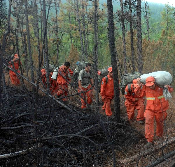Firefighters carry supplies in the Greater Hinggan Mountains of northeast China's Heilongjiang Province, July 2, 2010.