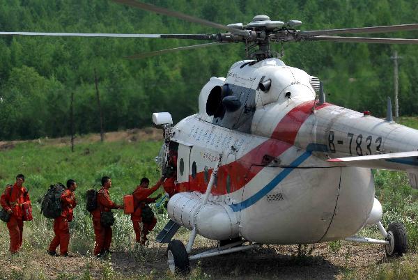 Firefighters board on a helicopter for fire scene in the Greater Hinggan Mountains of northeast China's Heilongjiang Province, July 2, 2010. 