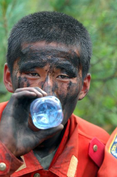 A firefighter drinks water when rests in Greater Hinggan Mountains of northeast China's Heilongjiang Province, July 2, 2010.