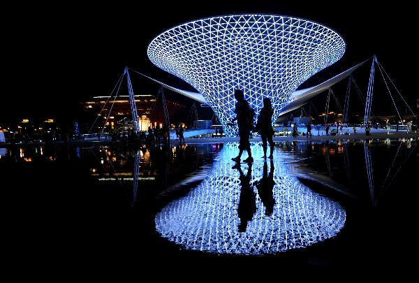Tourists pass by the Sun Valley at the World Expo Park in Shanghai, east China, on the night of July 2, 2010. More and more people prefer the night hiking in the World Expo Park to the daytime in order to avoid heat and crowded visitors. [Xinhua/Yan Yan] 