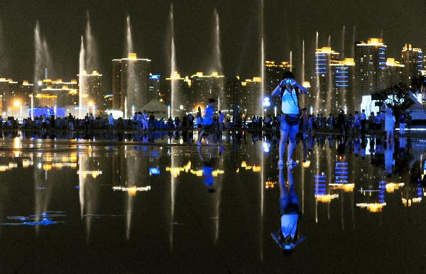 A tourist takes photos at the World Expo Park in Shanghai, east China, on the night of July 2, 2010. More and more people prefer the night hiking in the World Expo Park to the daytime in order to avoid heat and crowded visitors. [Xinhua/Yan Yan]