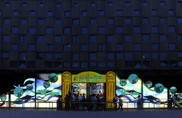 Tourists visit the Pavilion of Public Participation at the World Expo Park in Shanghai, east China, on the night of July 2, 2010. More and more people prefer the night hiking in the World Expo Park to the daytime in order to avoid heat and crowded visitors. [Xinhua/Yan Yan]