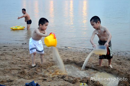  Two children play with water at the bank of the Minjiang River in Fuzhou in East China&apos;s Fujian province, July 3, 2010. [China Daily/Asianewsphoto]