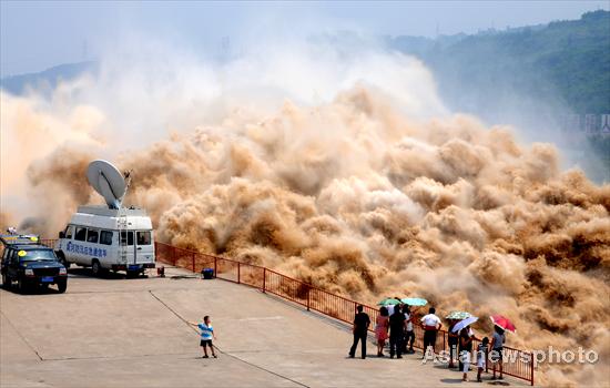 Spectators observe the desilting process at Xiaolangdi Reservoir on the Yellow River on July 4, 2010. The 10th desilting project of the Yellow River began on June 19 to filter out sand as high flows from upper reaches created a high sediment flow.[China Daily/Asianewsphoto] 