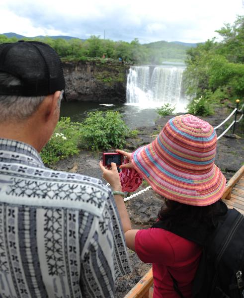 Tourists enjoy the scenery of the Diaoshuilou waterfall at Jingbo Lake in Mudanjiang City, northeast China's Heilongjiang Province, July 2, 2010. The waterfall here is fuller than usual this summer due to the frequent rainfall and snowfall in last winter and this spring. [Xinhua/Zhou Que]