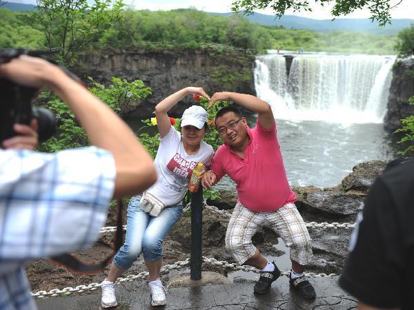 Tourists enjoy the scenery of the Diaoshuilou waterfall at Jingbo Lake in Mudanjiang City, northeast China's Heilongjiang Province, July 2, 2010. The waterfall here is fuller than usual this summer due to the frequent rainfall and snowfall in last winter and this spring. [Xinhua/Zhou Que] 