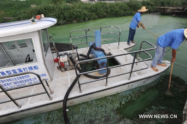 Environmental protection workers on a refloatation boat clear the blue-green algae on the Chaohu Lake in Hefei, east China&apos;s Anhui Province, July 3, 2010. Environmental protection department of Hefei and Chaohu City organized workers to clear the blue-green algae overrunning on the Chaohu Lake recently. [Xinhua]