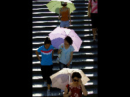 Pedestrians under umbrella walk into a underpass in Beijing, capital of China, July 5, 2010. Chinese meteorological authority said Monday hot weather continues to scorch many parts of the country.  [Xinhua]